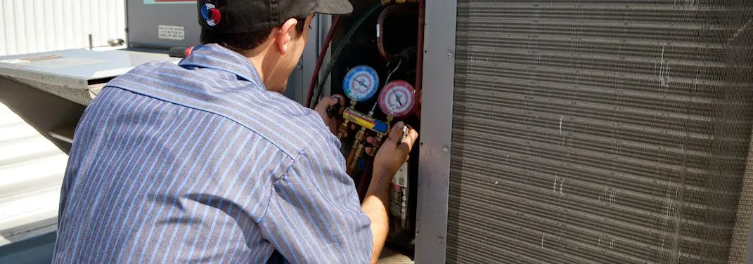 HVAC technician servicing a condenser unit in Winchester