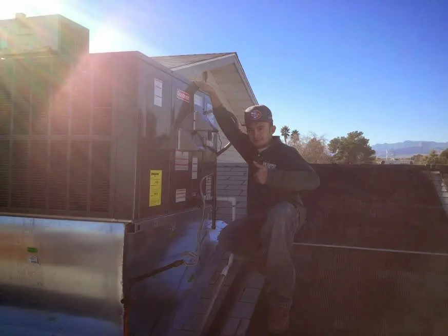 HVAC technician performing Air Duct Cleaning on a rooftop unit in Winchester